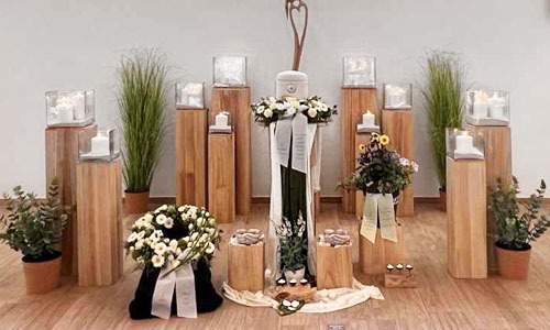 Ein Urne inmitten von Kerzen und Blumen. Trauerarrangement. Auch mit einem Altar möglich. Für Trauerbewältigung.